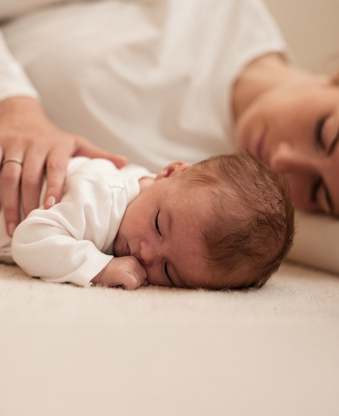 Nouveau-né endormi sur le ventre, allongé près de sa mère.