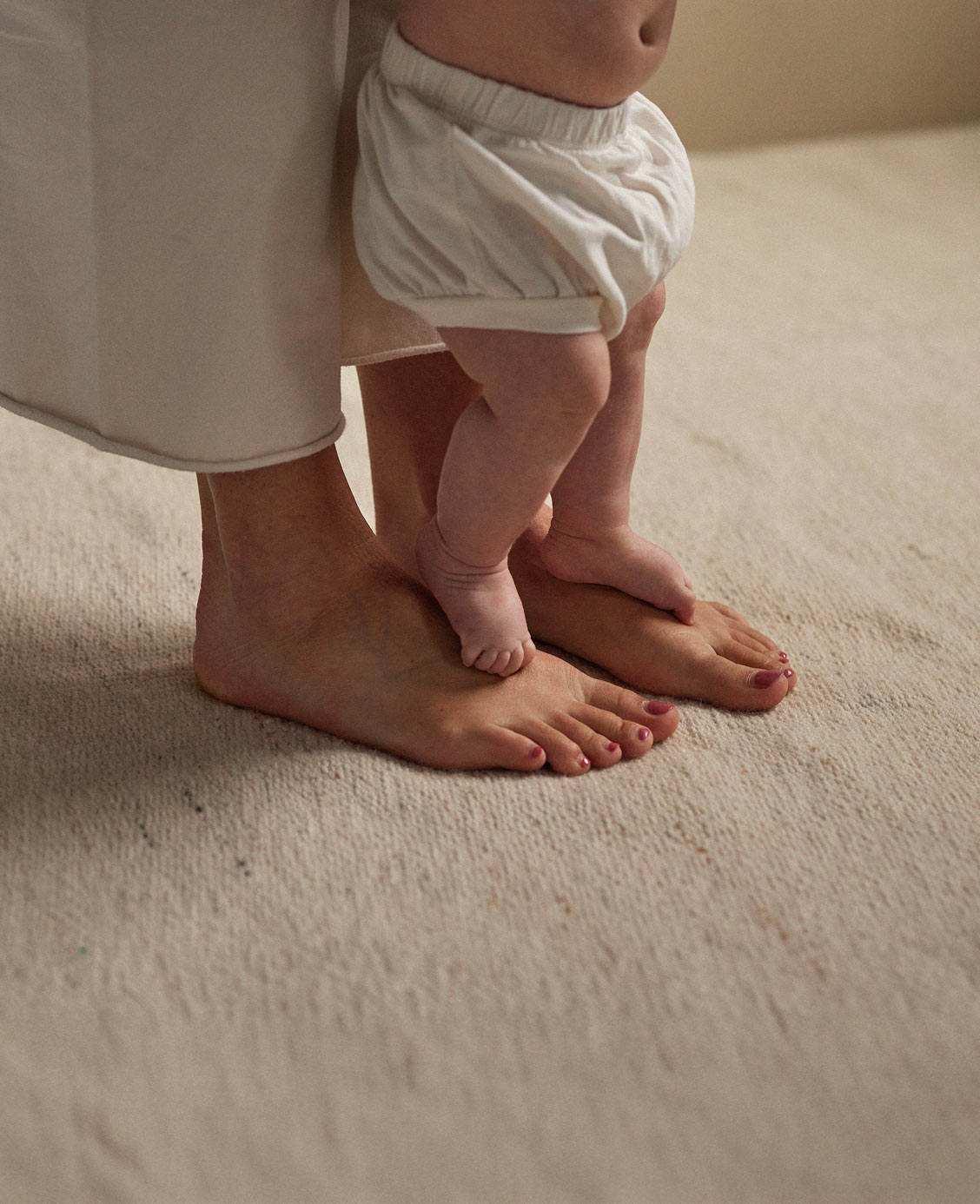 Pieds d’un bébé posés sur ceux d’un adulte, symbolisant le lien familial.